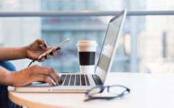 woman using laptop with phone