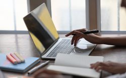 hand on laptop with pen